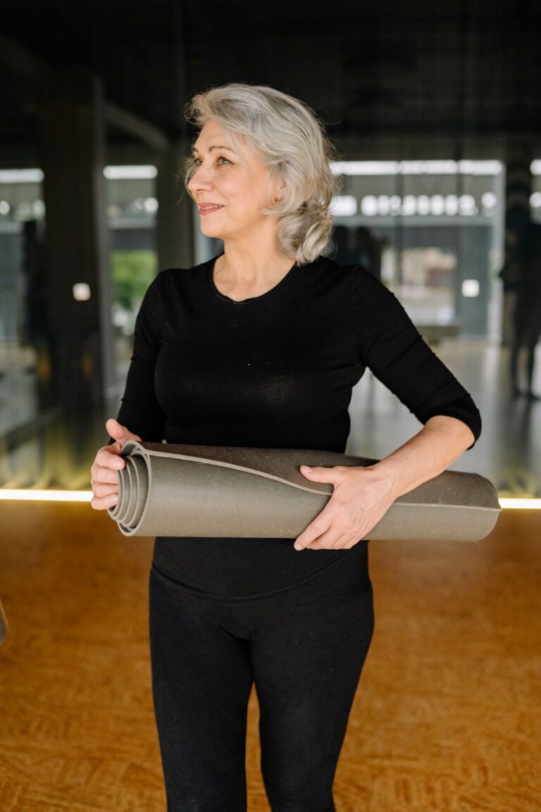 Woman in activewear holding a yoga mat