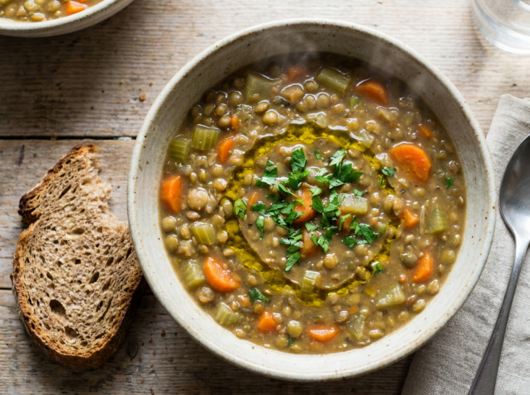 A bowl of hearty lentil and vegetable soup with parsley and crusty bread